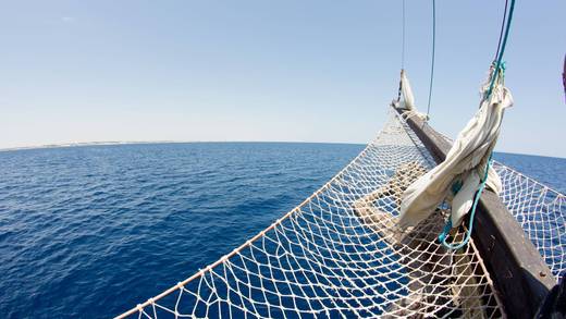Boegspriet en kluivernet van een zeilschip boven een blauwe zee