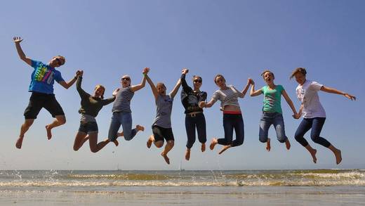 Scholieren springen samen op het drooggevallen Wad