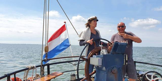 Twee gasten aan het stuurwiel van een zeilschip