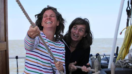 Twee gasten trekken samen aan een lijn aan boord