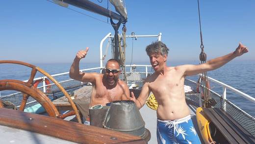 Vrienden bij het stuurwiel tijdens een vrijgezellenfeest op een zeilschip